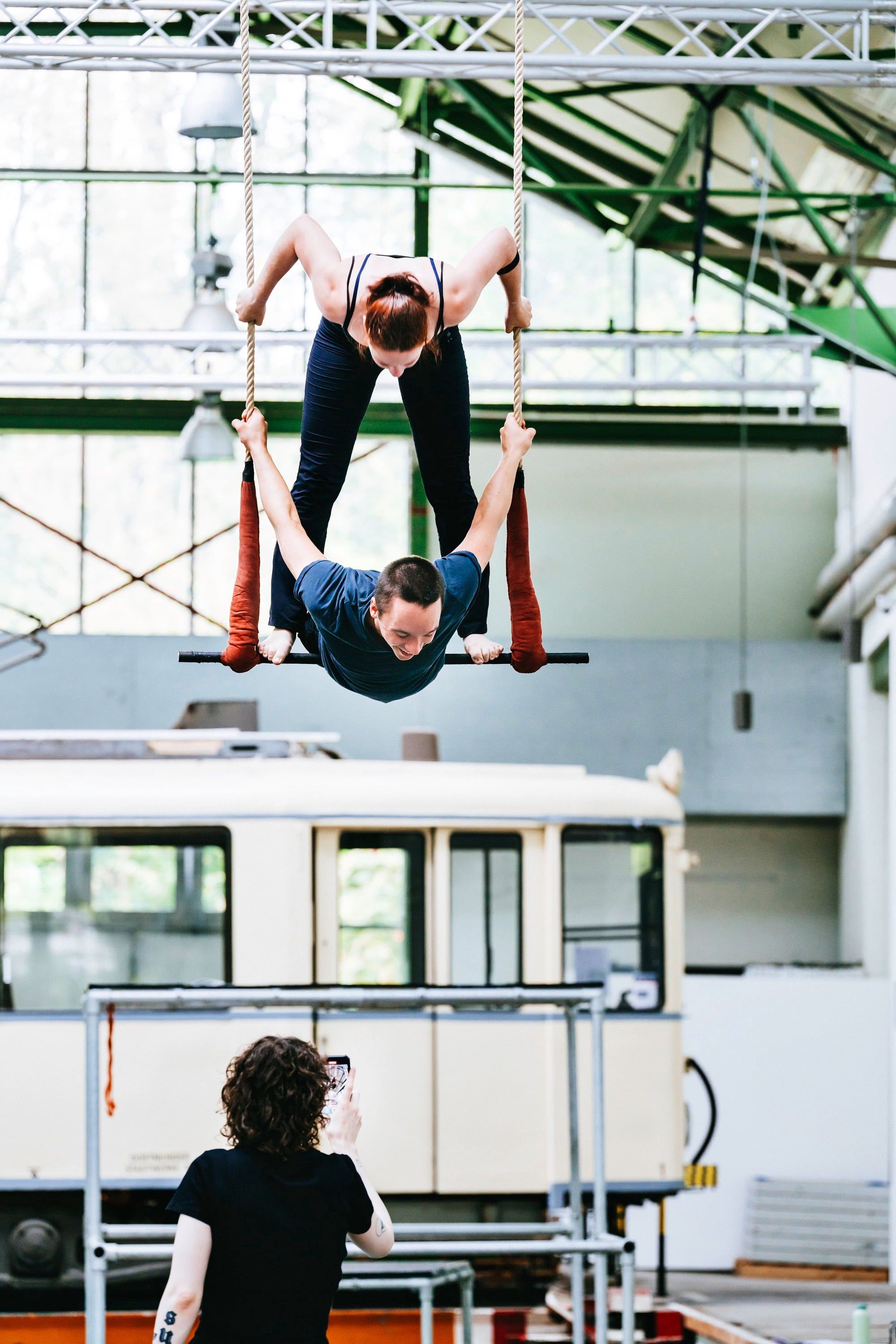 Two teenagers performing acrobatics on a trapeze