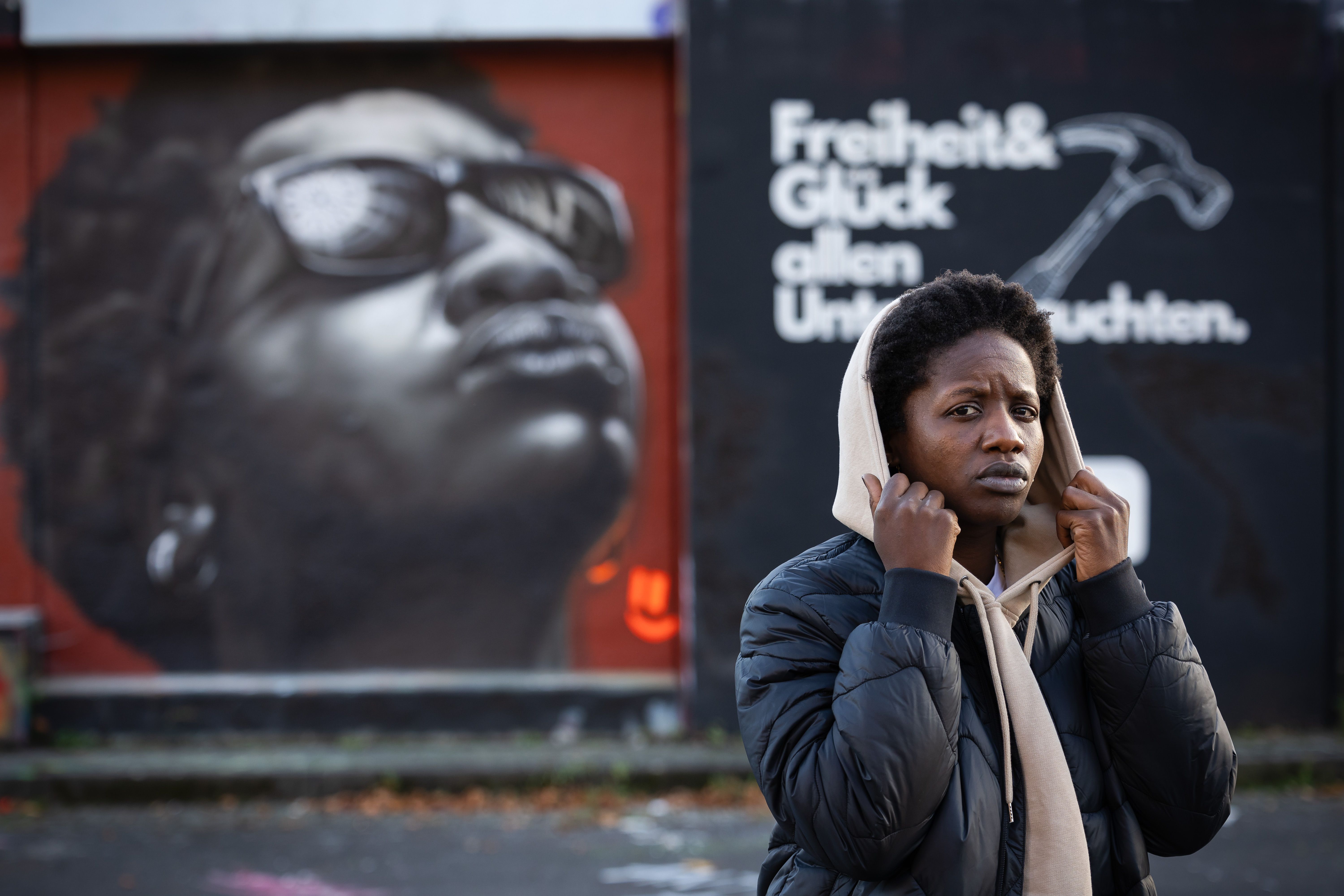 Woman with hood in front of wall with graffiti