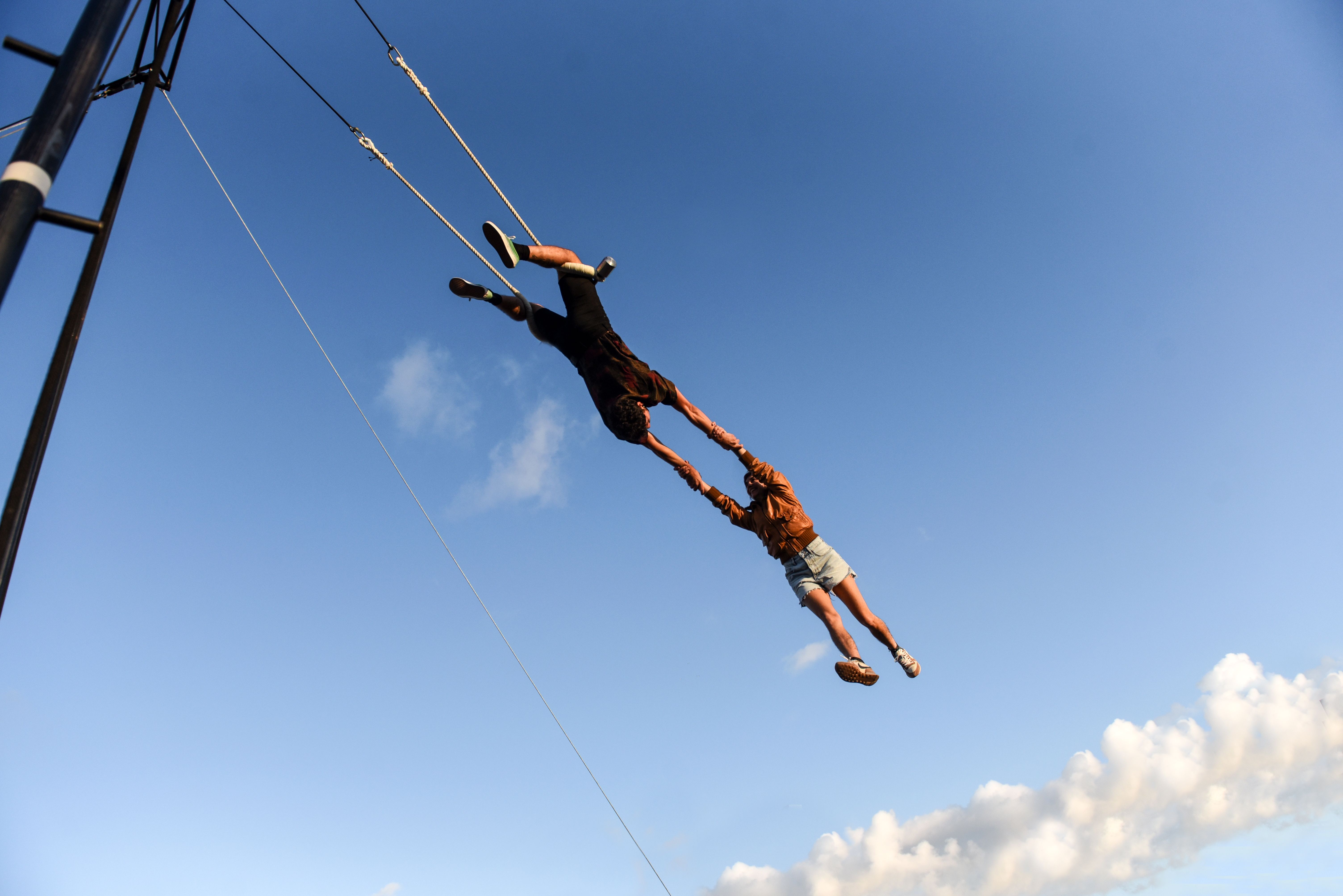 Two artists can be seen on the trapeze in the open air.