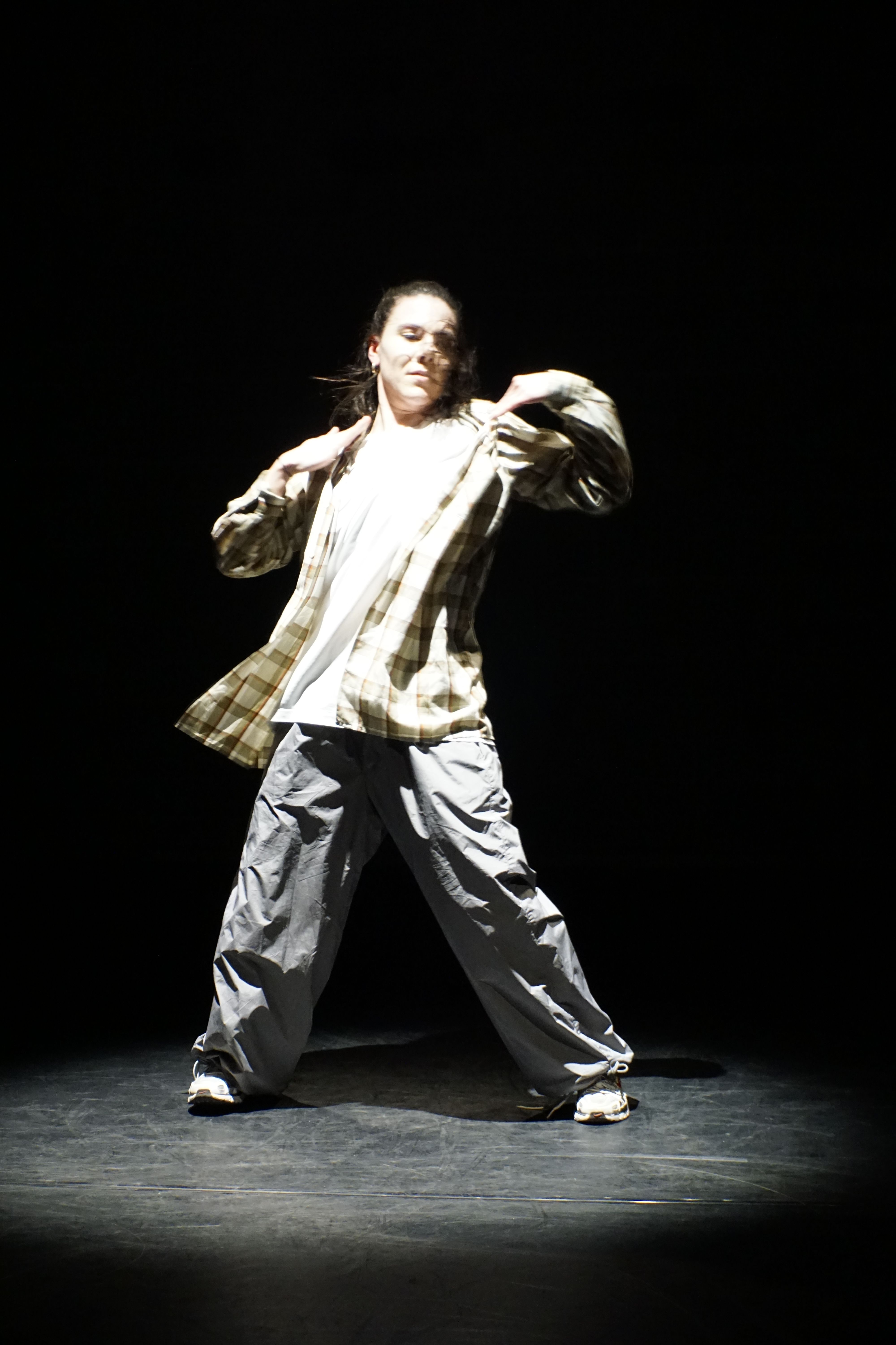 Person dancing onstage under spotlight 