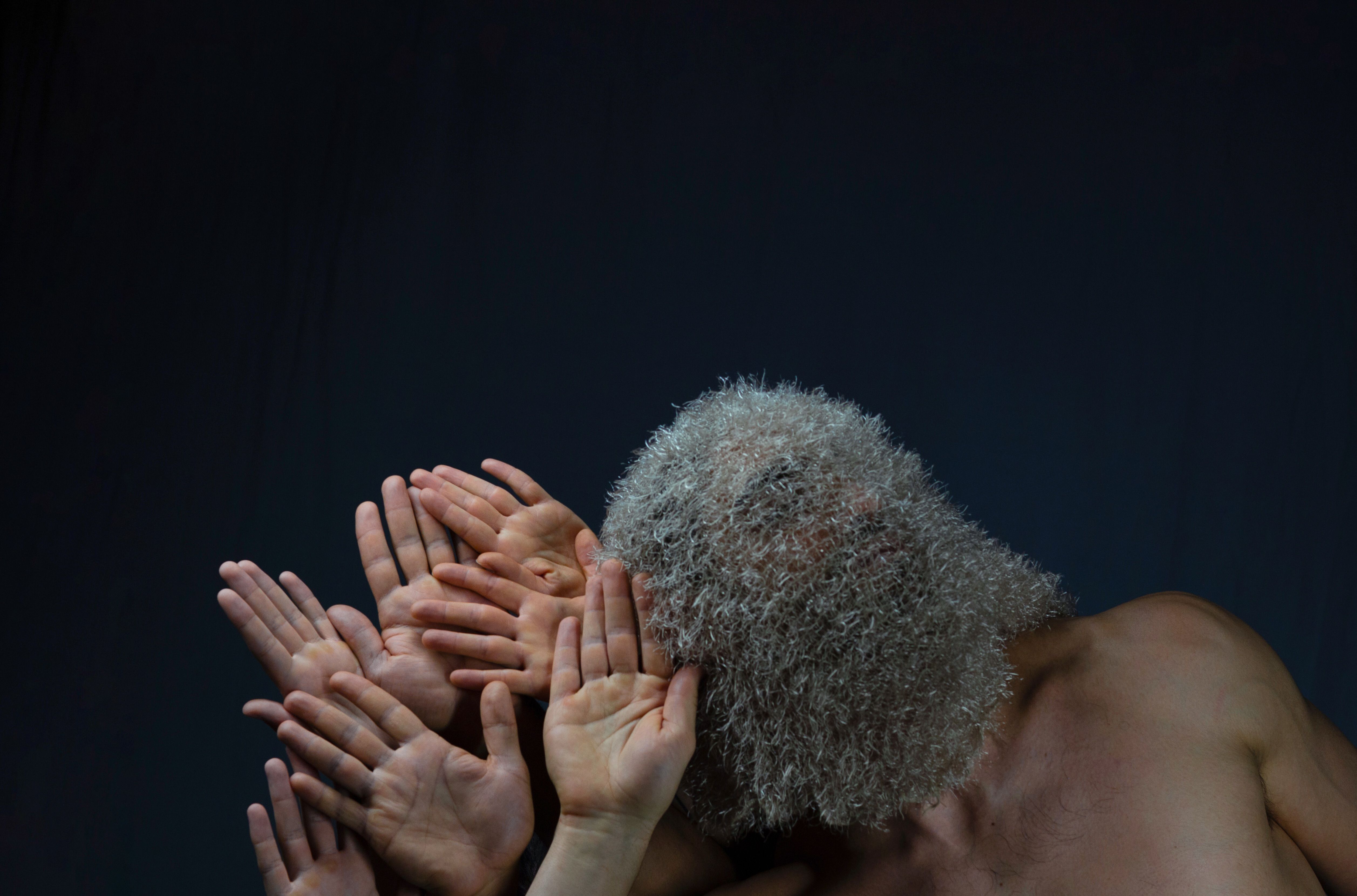 A person holding a hand to their ear and other hands next to them