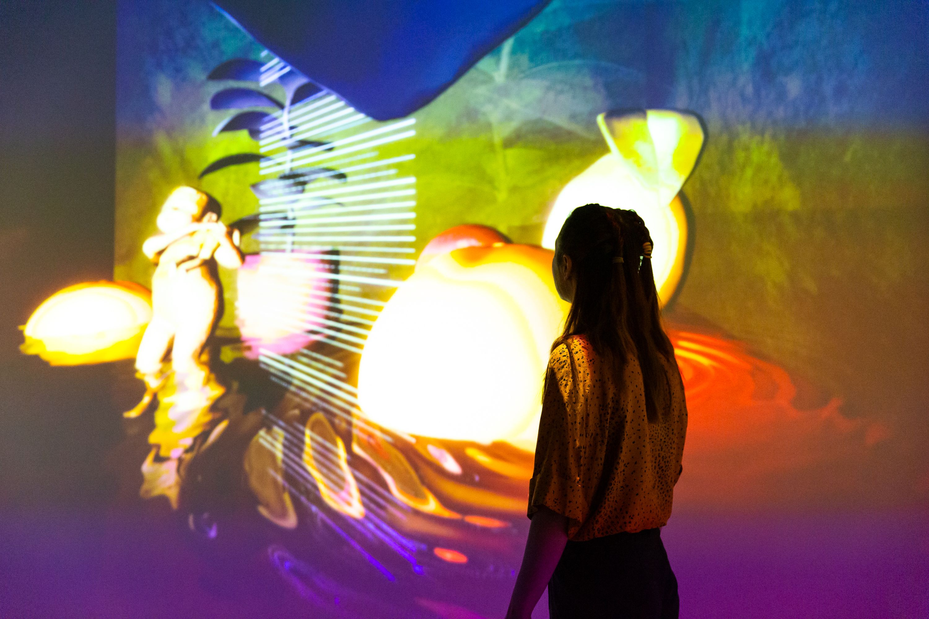 You can see a person in front of a colorful projection.