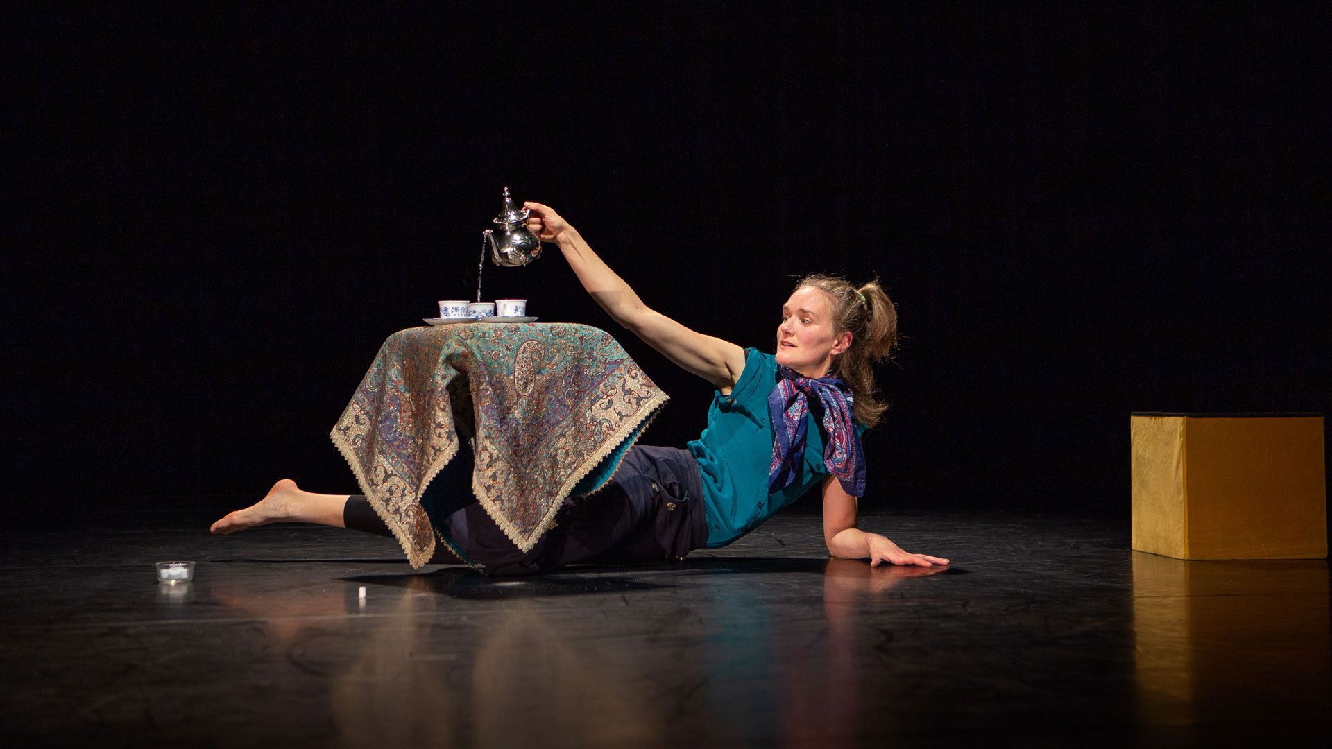 Acrobat lying on the floor and pouring tea into cups