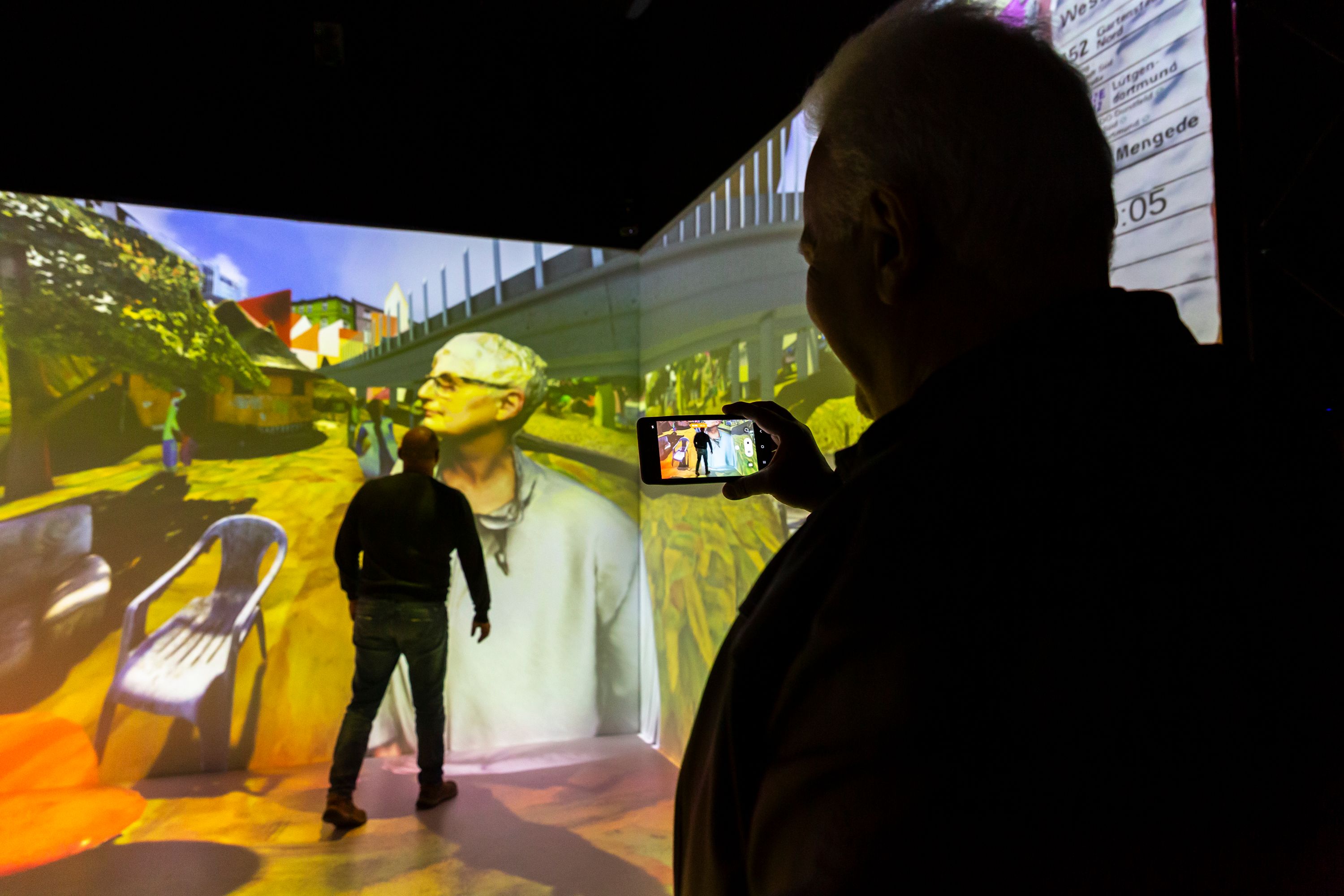person standing in front of a wall with light projection and holding a mobile phone