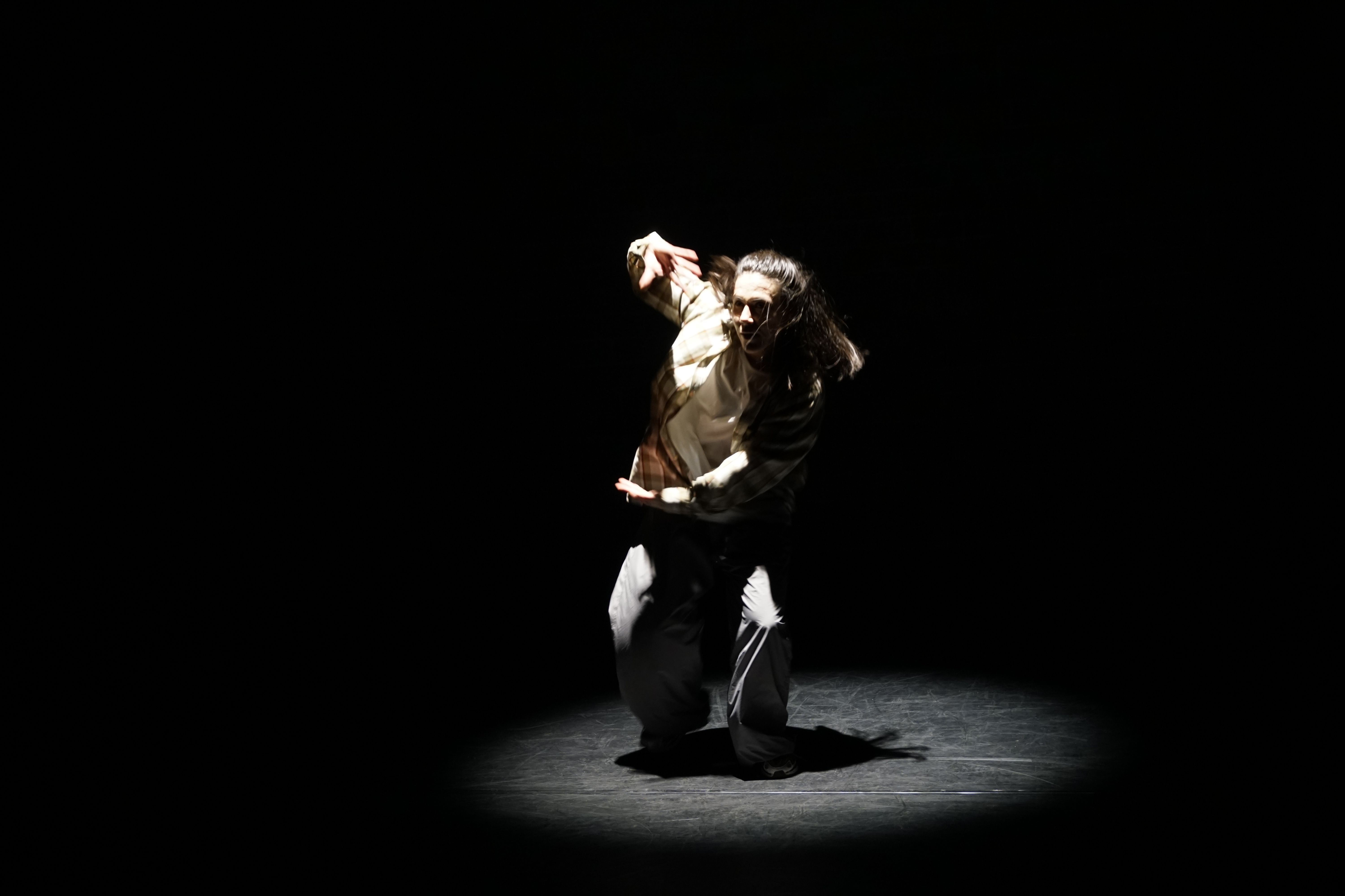Person dancing onstage under spotlight