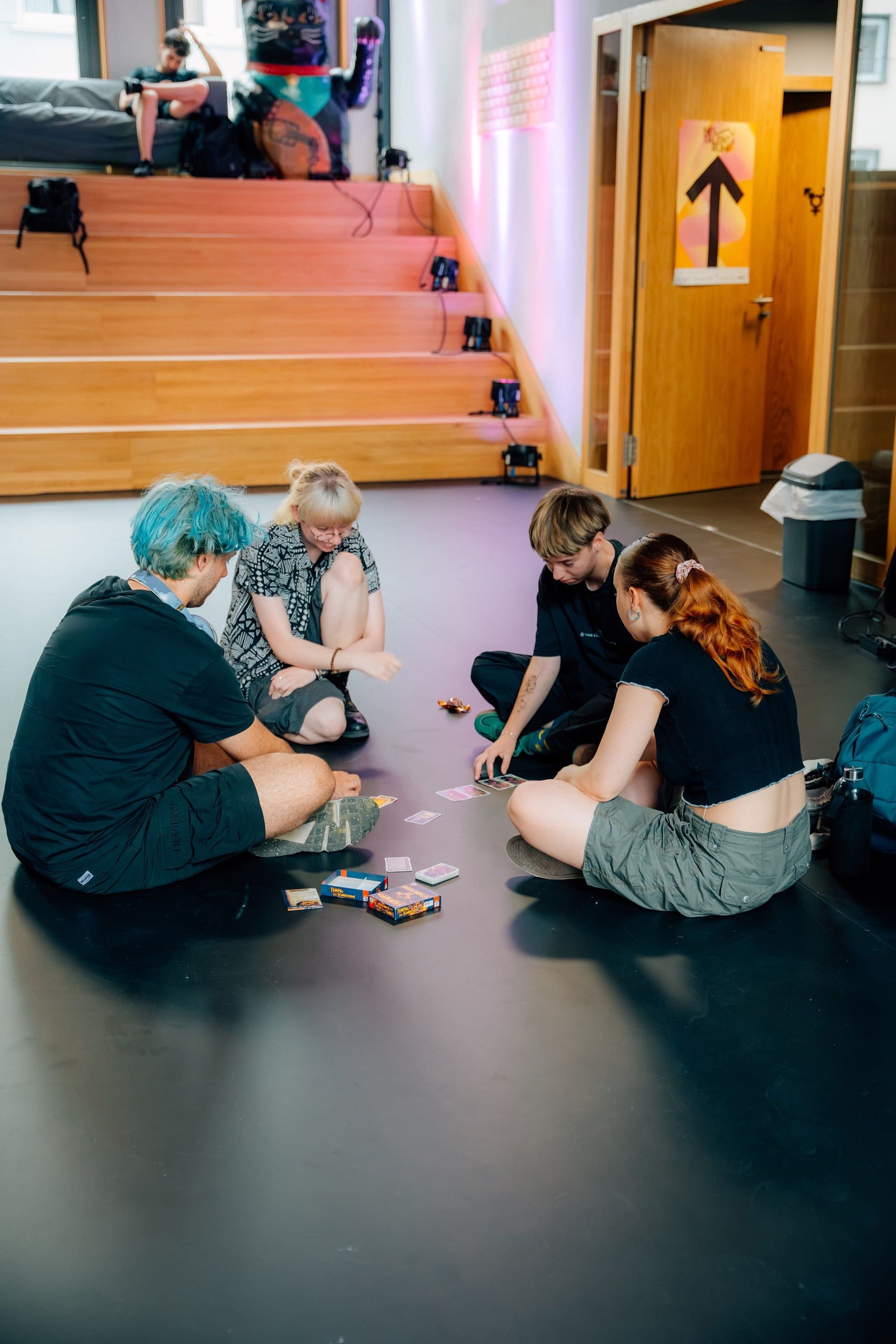 Young people sitting on the floor playing cards