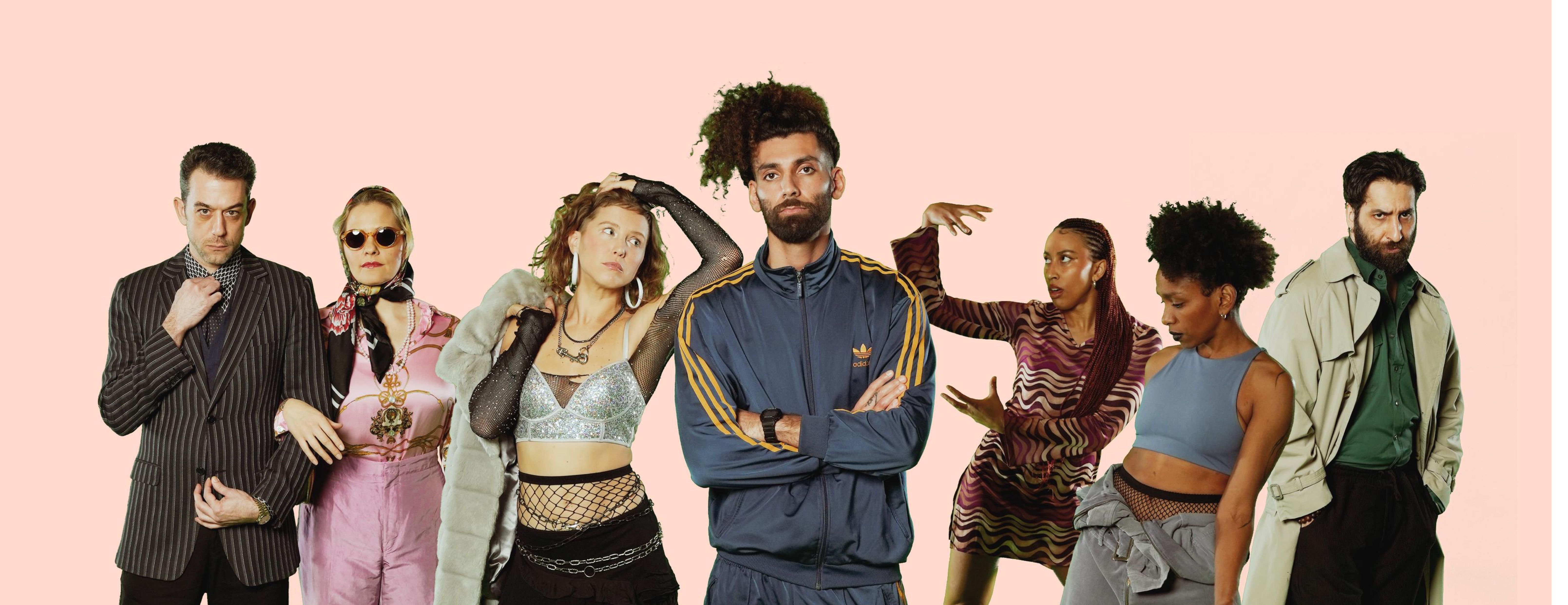 A group of people are lined up in a row. They are either looking at the camera or at the person in the middle with their arms crossed in front of their chest.