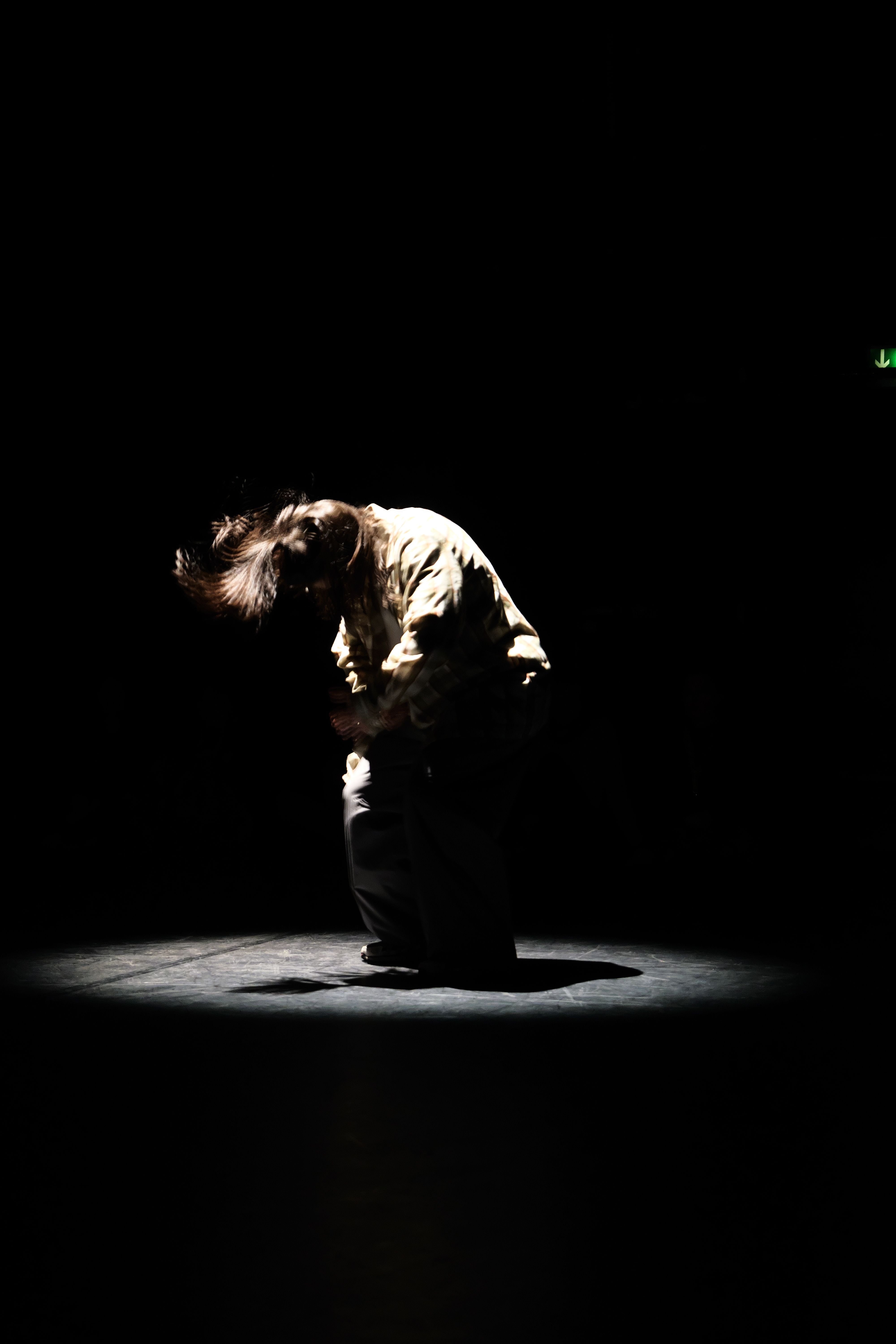 Person dancing onstage under spotlight 