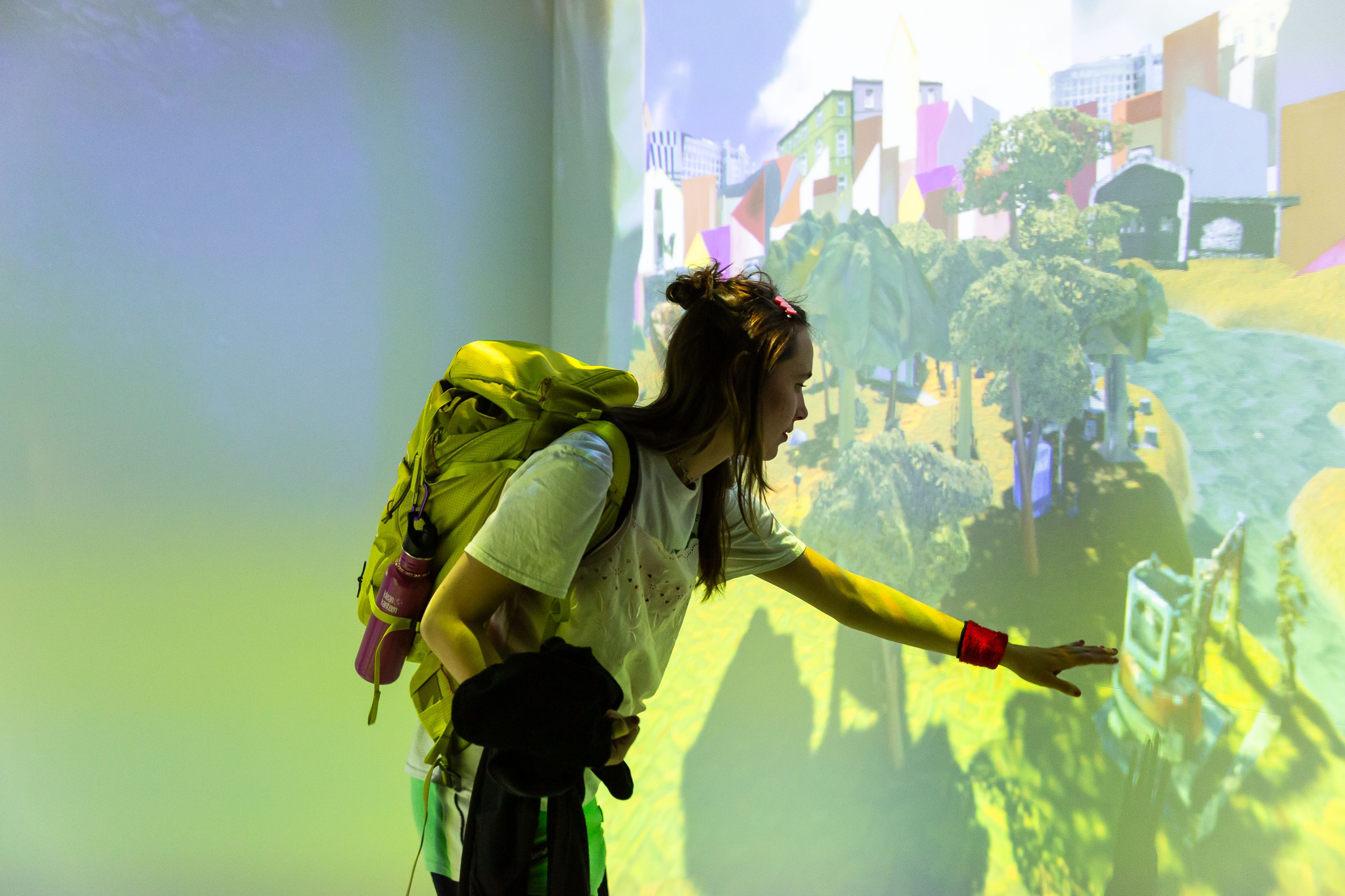 Person standing in front of a wall with a light projection and stretching out their hand towards it