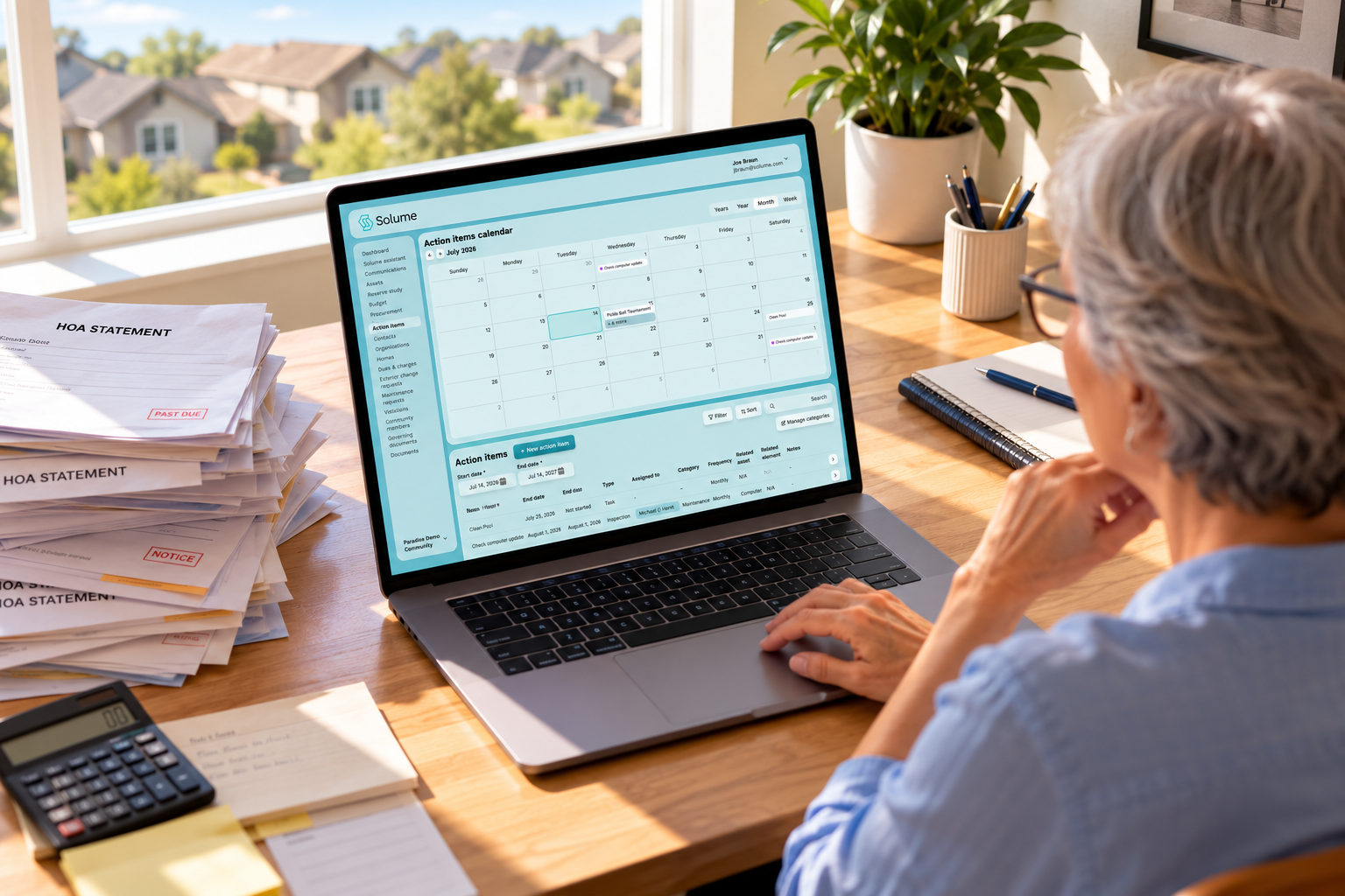 Older HOA treasurer reviewing the Solume action items calendar and task management dashboard on a laptop at a sunlit home office desk.
