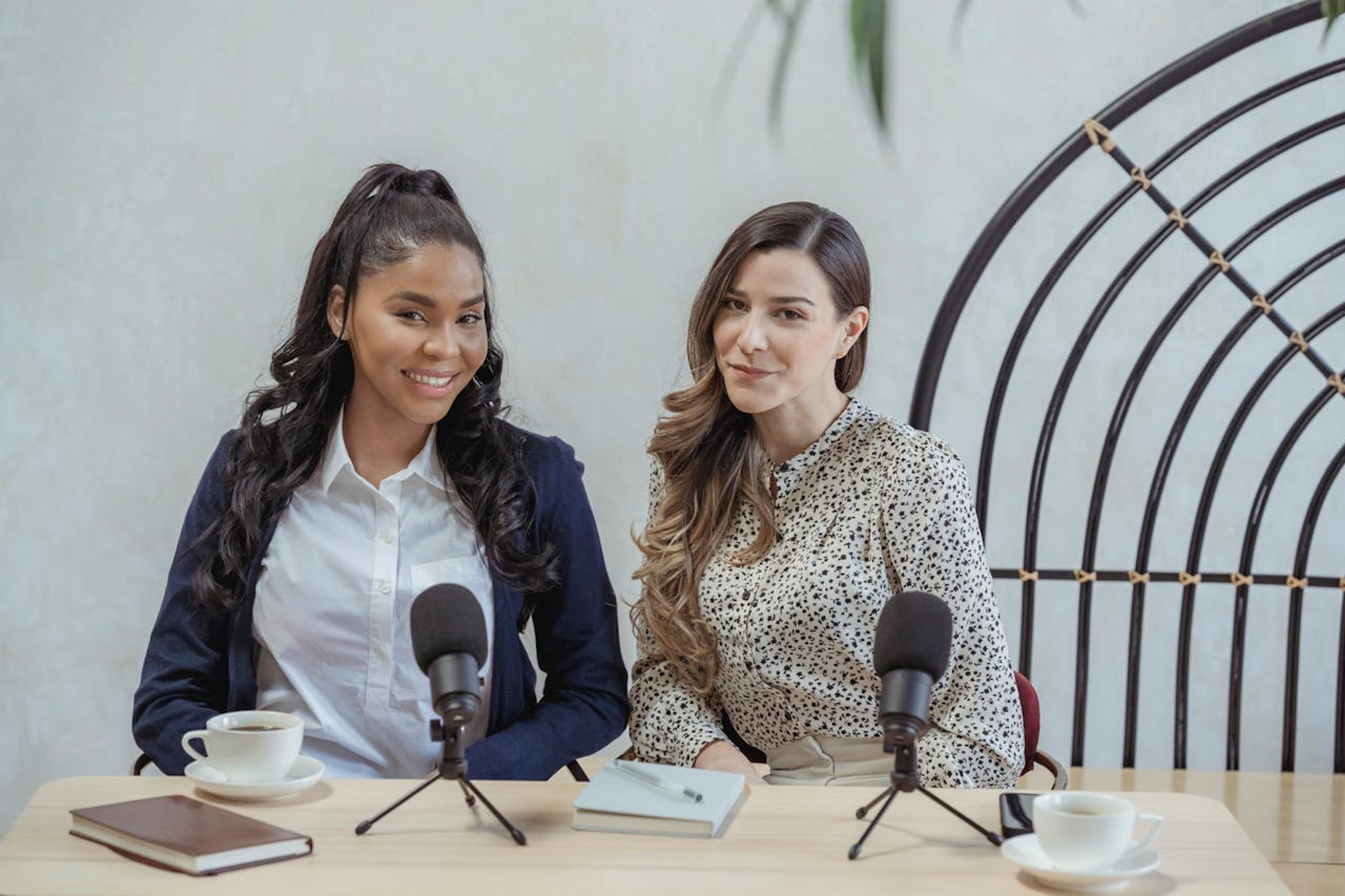 2 girls sitting at a desk with a microphone