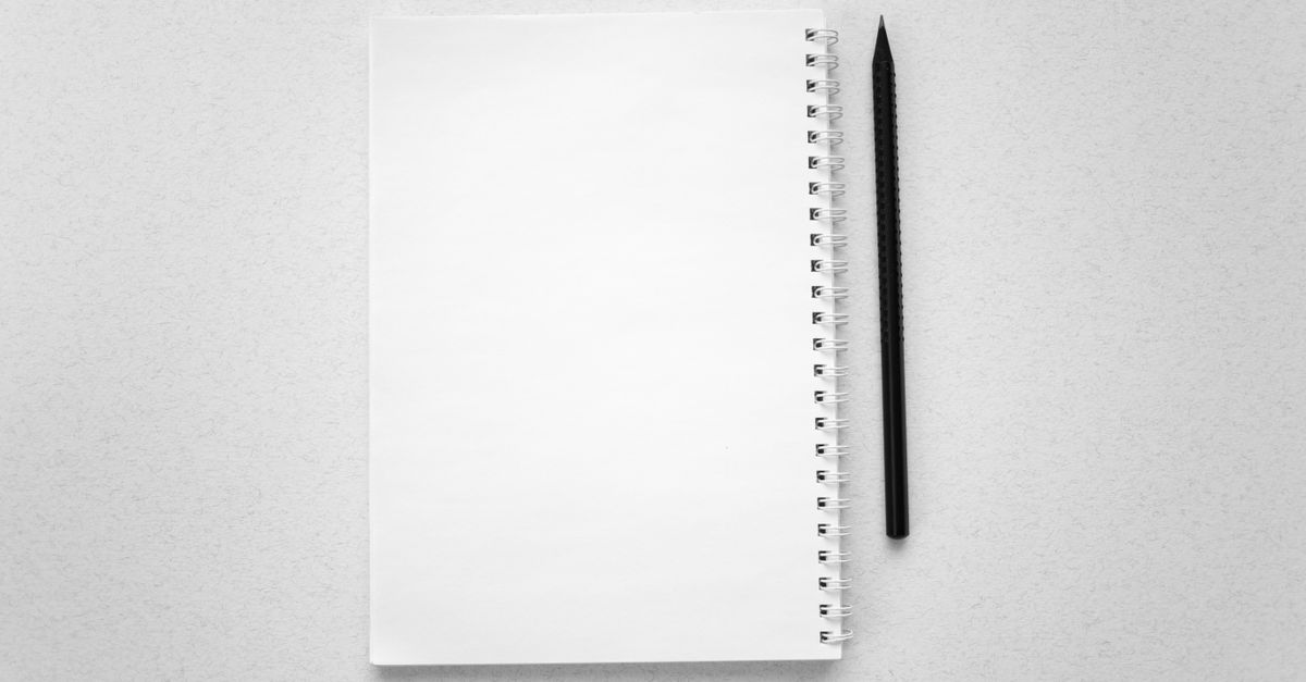 A blank spiral notebook and pencil on a white surface.