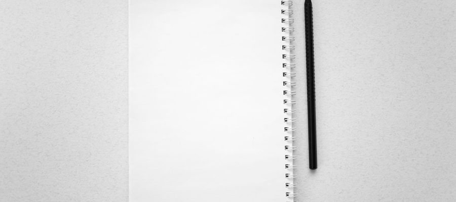 A blank spiral notebook and pencil on a white surface.