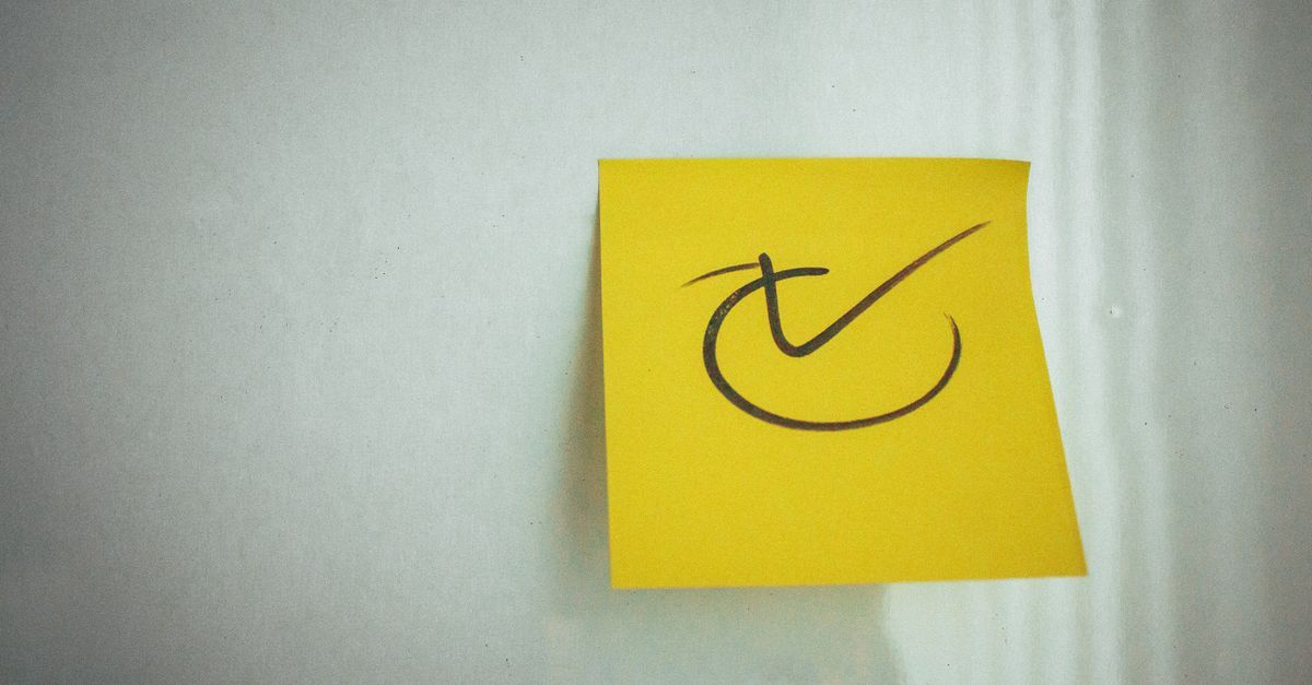A yellow sticky note with a check mark on a white surface.