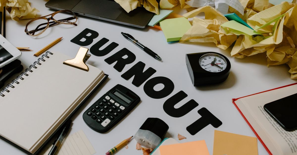 A clock, calculator and crumpled papers on a cluttered desk.