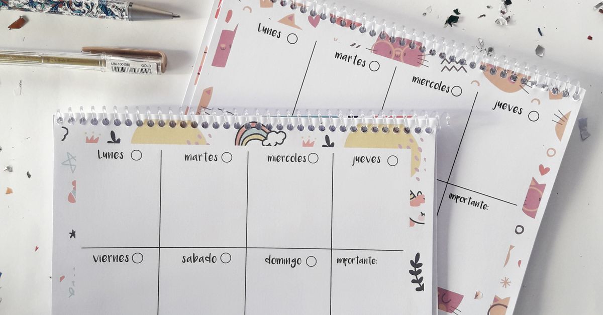Colourful weekly planners, pens and confetti on a desk.