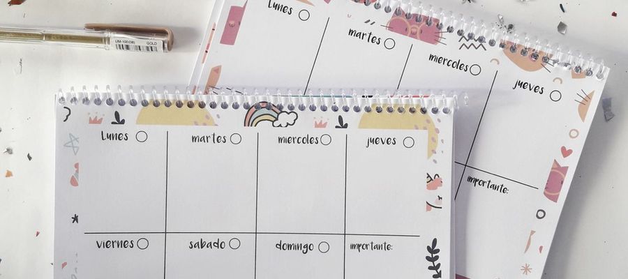 Colourful weekly planners, pens and confetti on a desk.