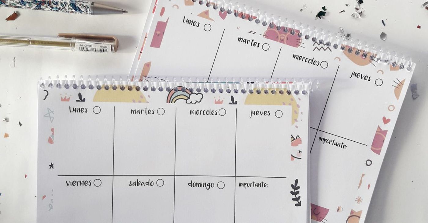 Colourful weekly planners, pens and confetti on a desk.