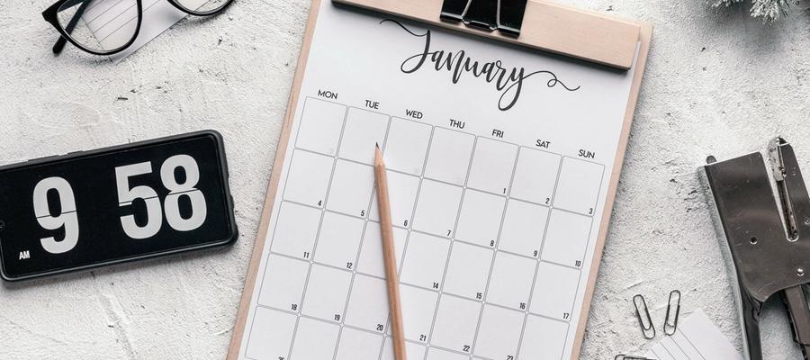 Calendar sheet on a clipboard beside a flip clock and stationery.