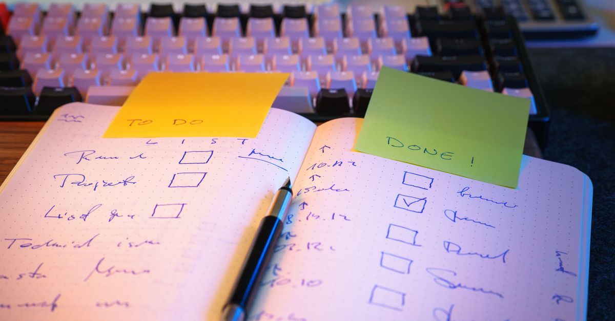 A notebook checklist with marked tasks and sticky notes on a desk.