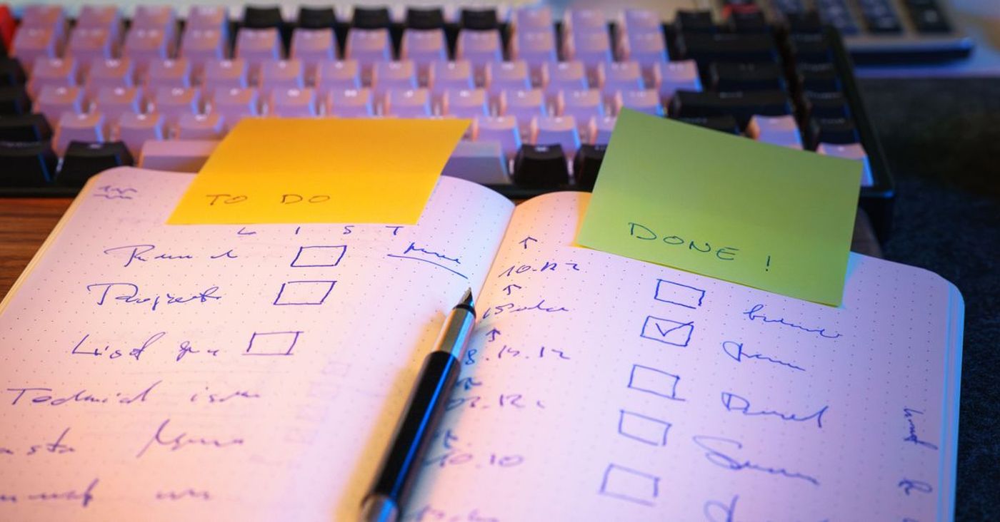 A notebook checklist with marked tasks and sticky notes on a desk.