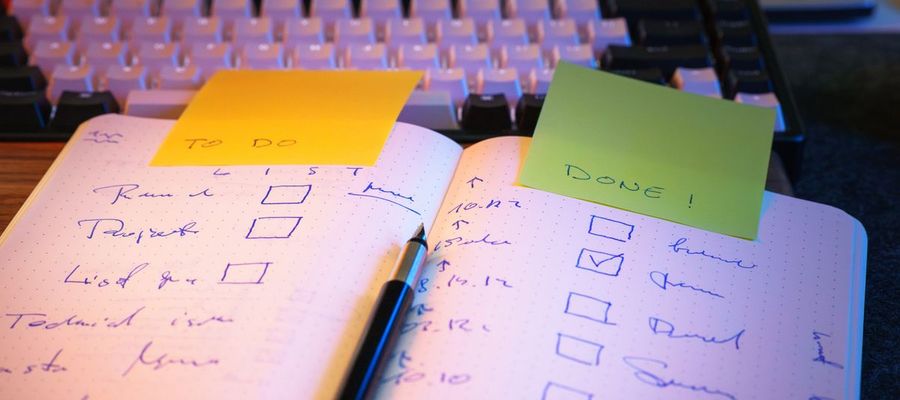 A notebook checklist with marked tasks and sticky notes on a desk.