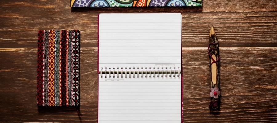 Colorful notebooks and a pencil arranged on a wooden table.