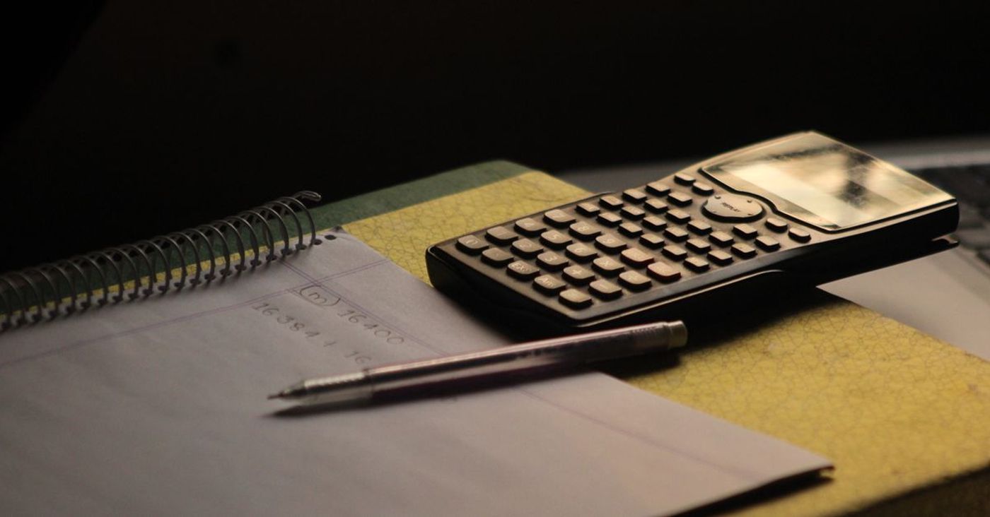 A calculator and a notebook on a study desk.
