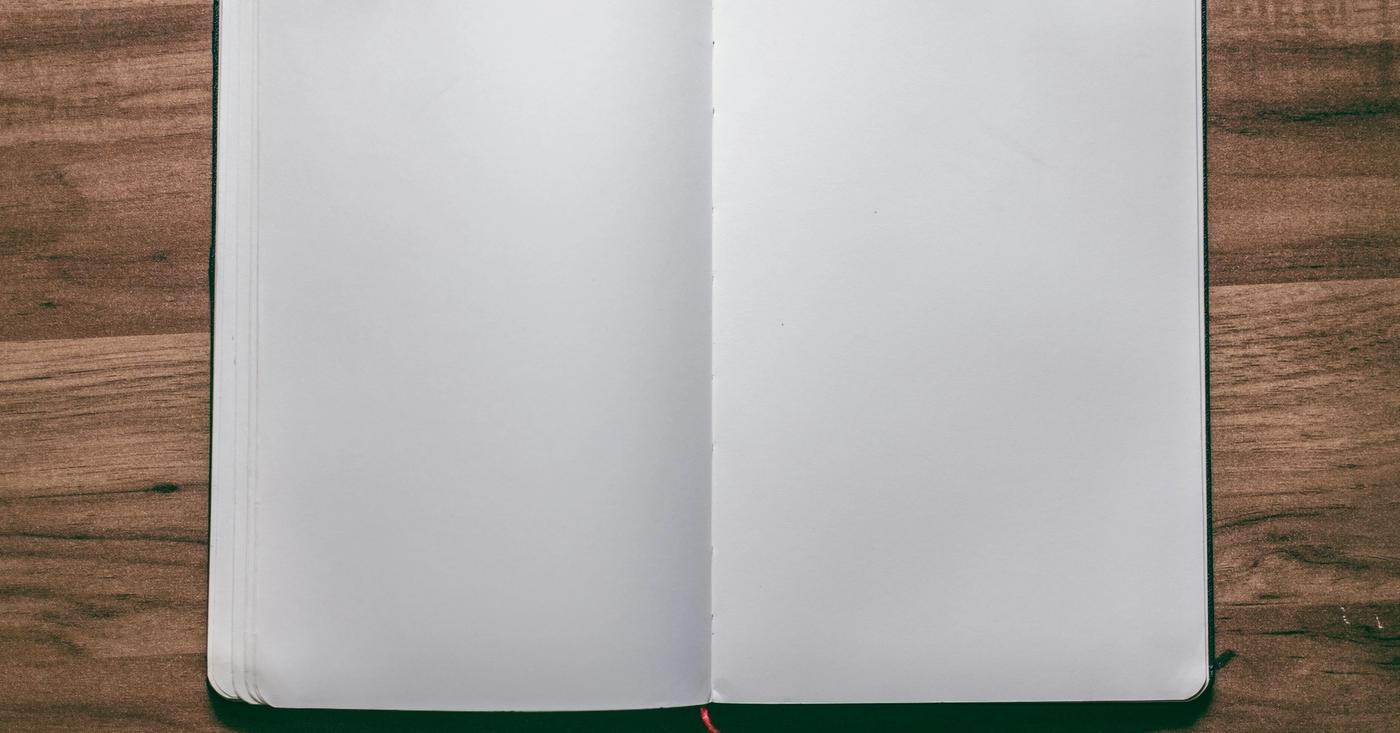 Open blank notebook on a wooden desk.
