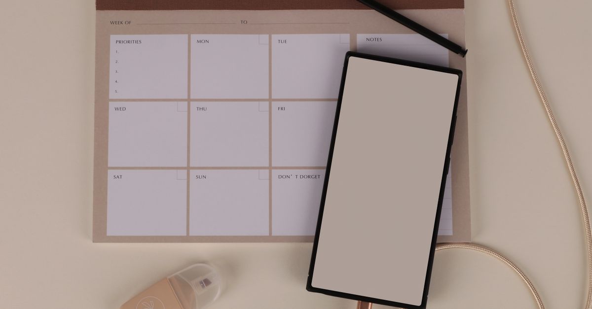 A blank weekly planner arranged with a phone and stationery.