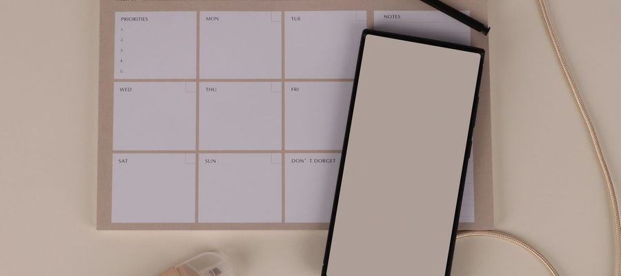 A blank weekly planner arranged with a phone and stationery.