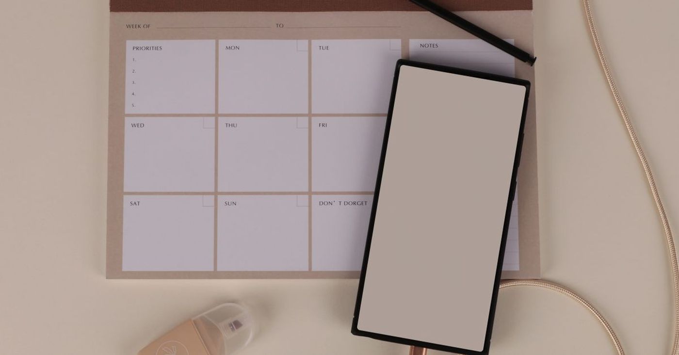 A blank weekly planner arranged with a phone and stationery.