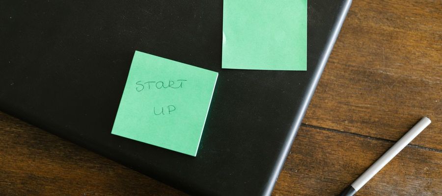 Green sticky notes and a pen resting on a laptop.