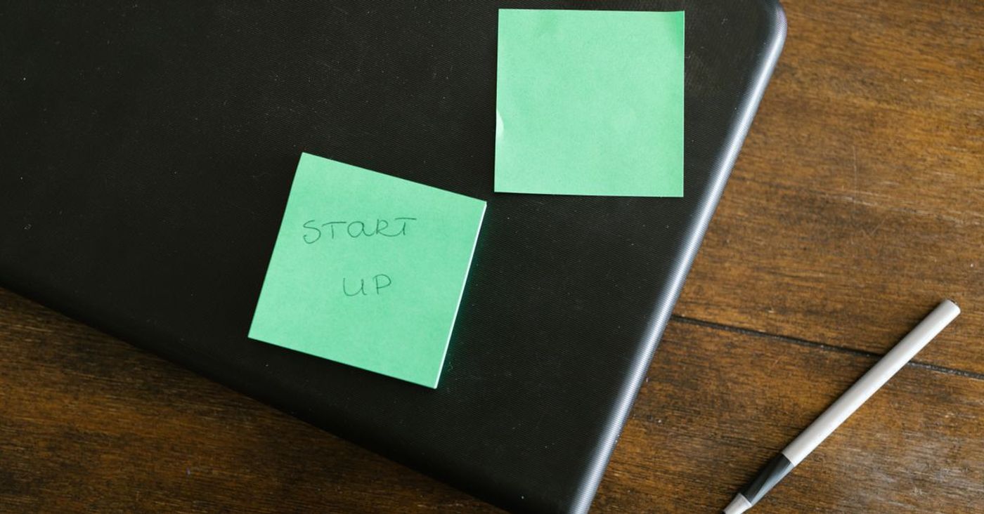 Green sticky notes and a pen resting on a laptop.