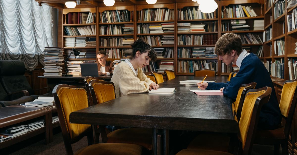 Students study at tables in a traditional library.