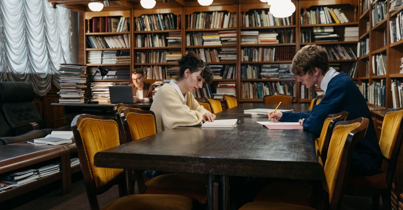 Students study at tables in a traditional library.