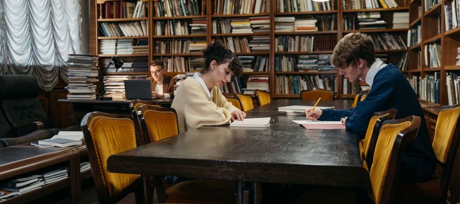 Students study at tables in a traditional library.