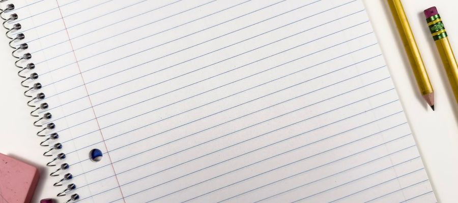 A spiral notebook with pencils and an eraser, viewed from above.