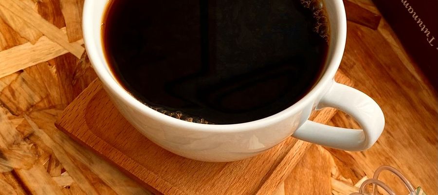 Coffee, books and a notebook on a wooden table.