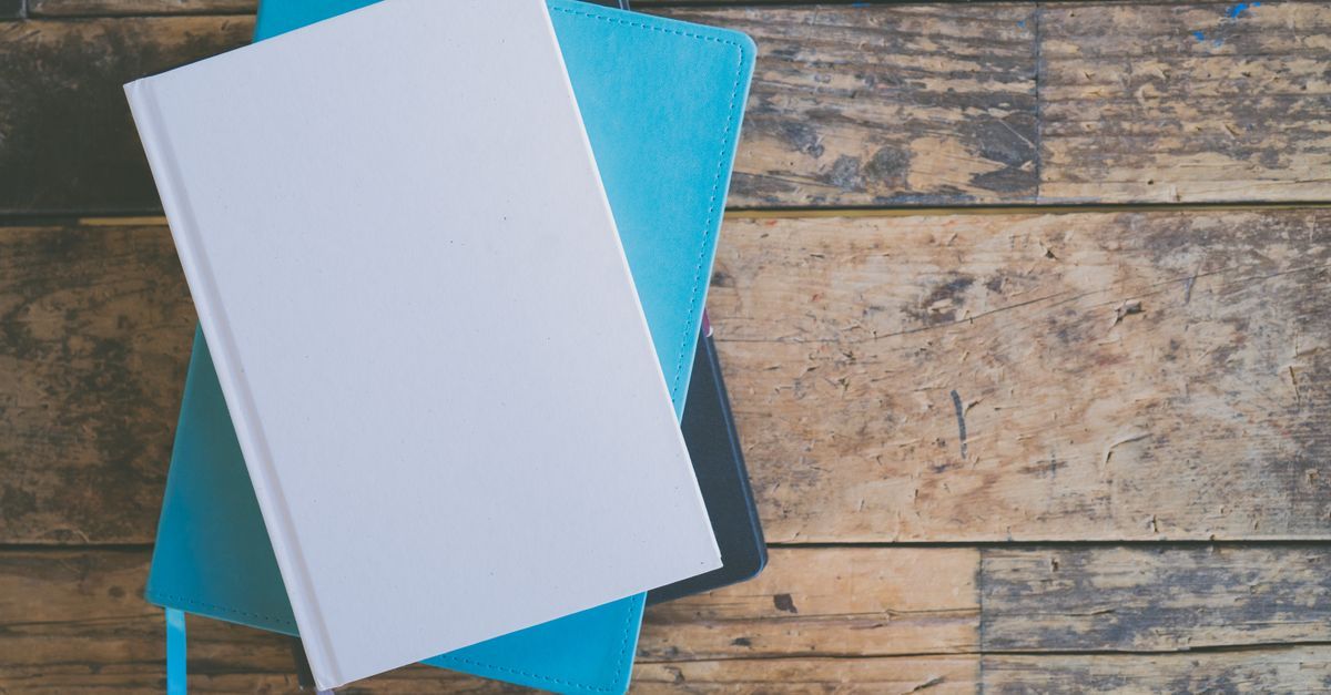 Stacked notebooks viewed from above on a wooden surface.