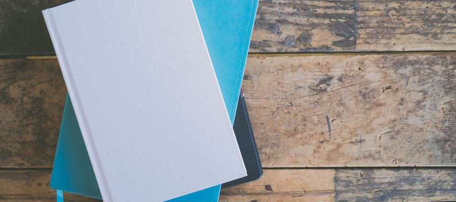 Stacked notebooks viewed from above on a wooden surface.