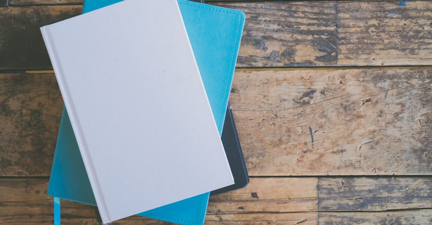 Stacked notebooks viewed from above on a wooden surface.