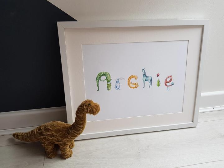 Framed personalised name print for Archie beside a toy dinosaur