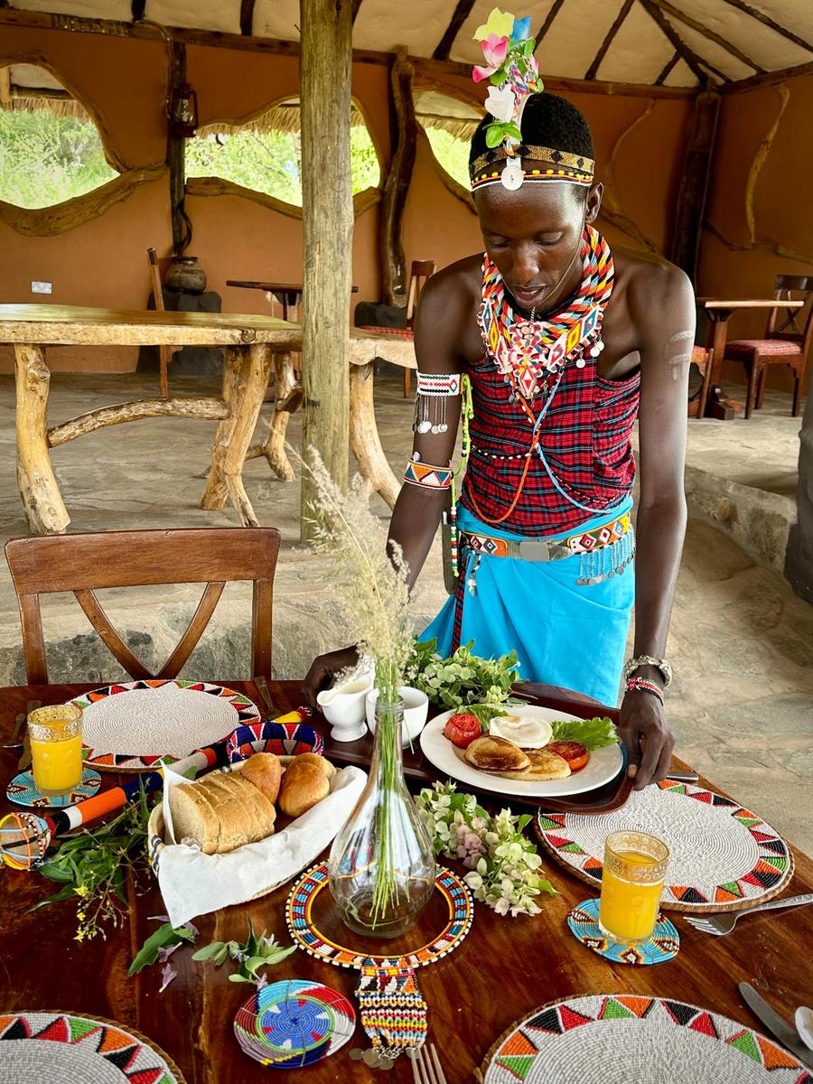 Maasai host serving breakfast in camp