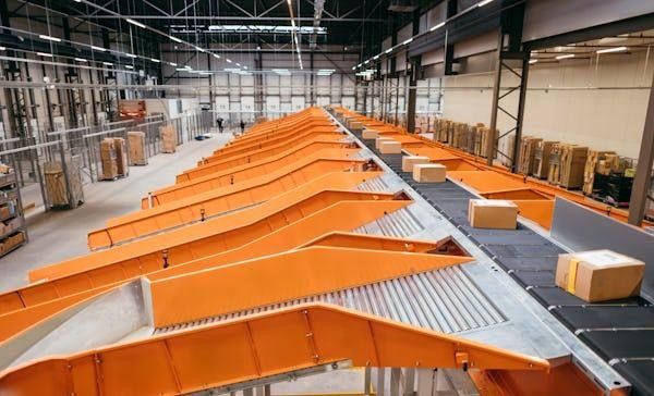 Sliding shoe sorter diverting cartons along orange sortation lanes