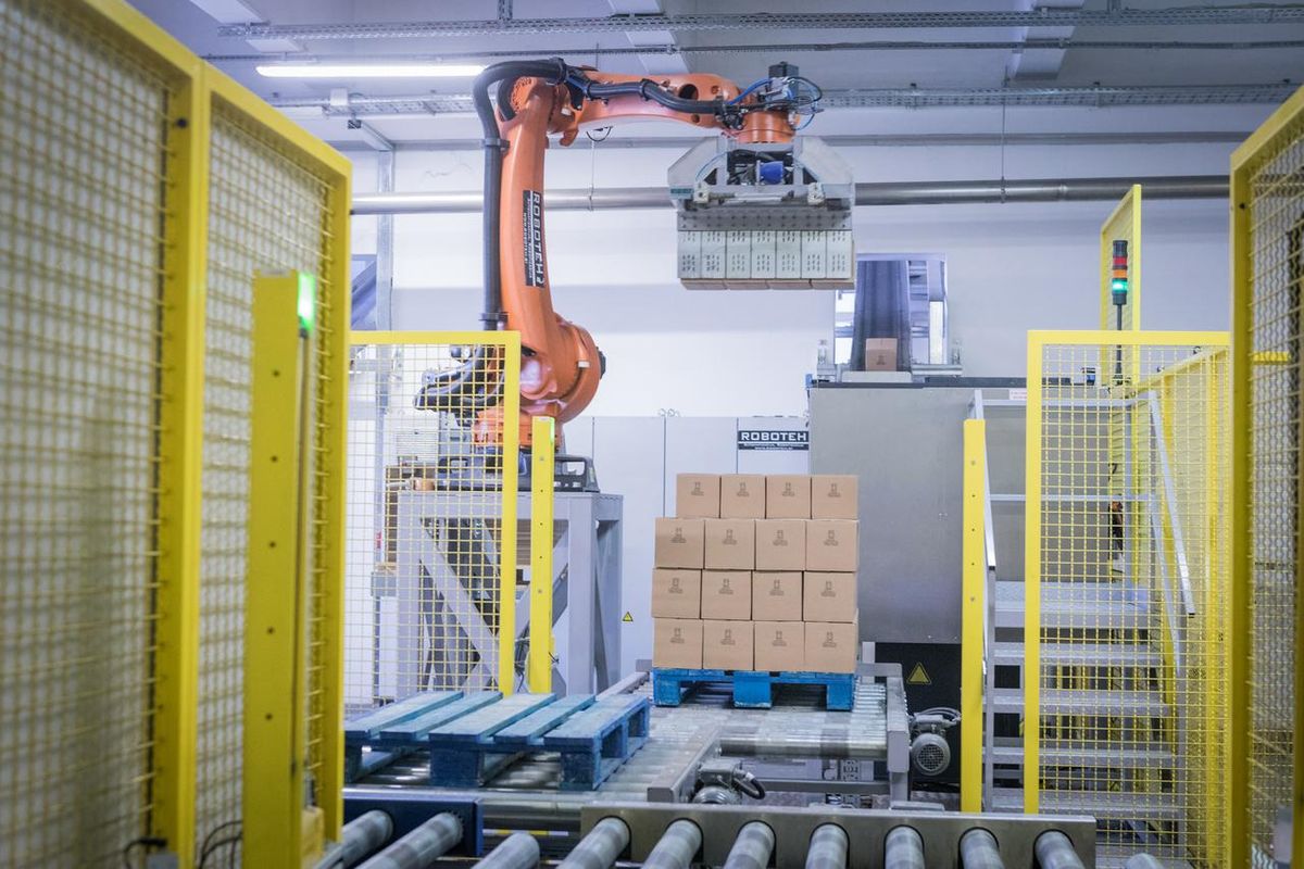 Robotic palletizing arm stacking cartons onto a pallet