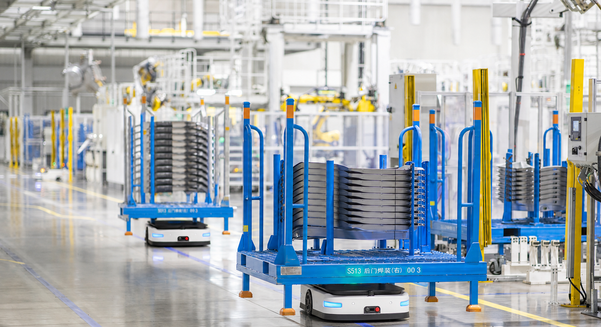 Lifting automated robot moving a loaded material cart in a manufacturing facility