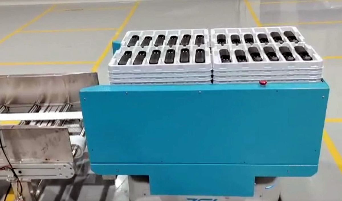 AGV carrying trays for empty-tray delivery and full-material pickup in an injection molding logistics cycle