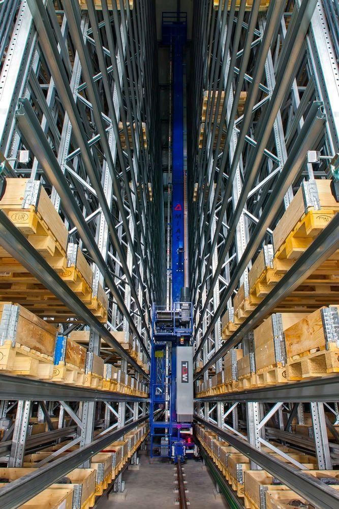 Stacker crane centered between tall pallet racks in a high-bay automated storage system