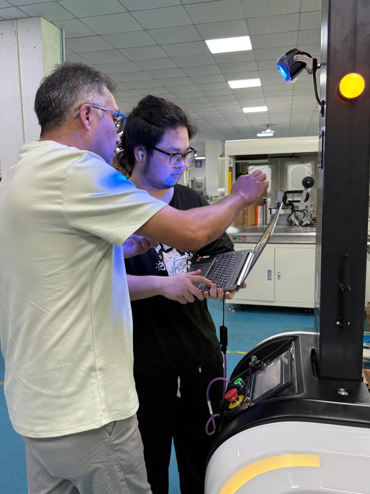 Engineers reviewing an autonomous forklift AGV during on-site commissioning